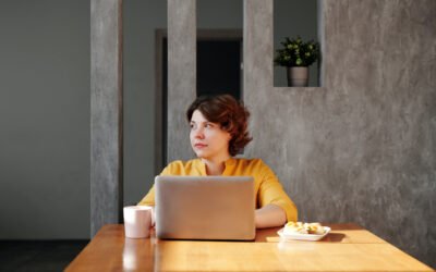 Lady sitting at table with her laptop, coffee mug and breakfast