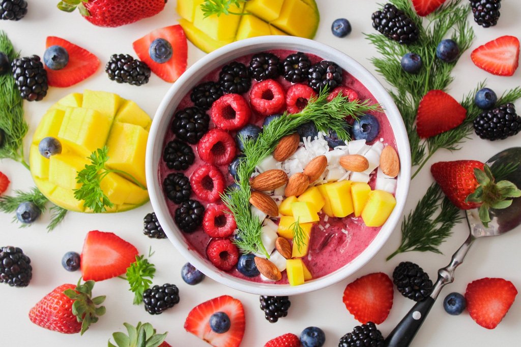 Fruit filled breakfast bowl surrounded by more fruit