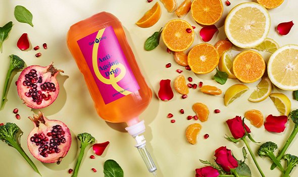 Anti Ageing IV Drip bottle surrounded by citrus fruits and vegetables