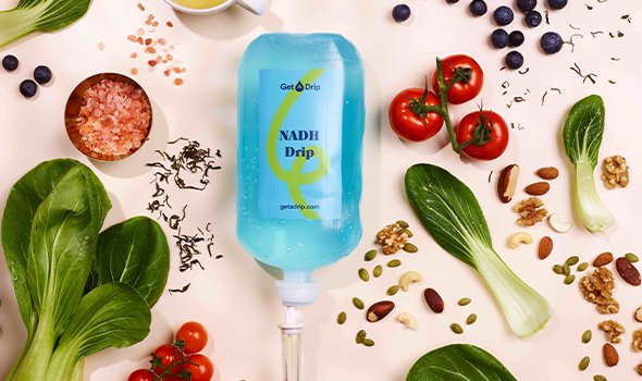 NADH IV-infuusfles omringd door fruit, groenten, noten en kruiden