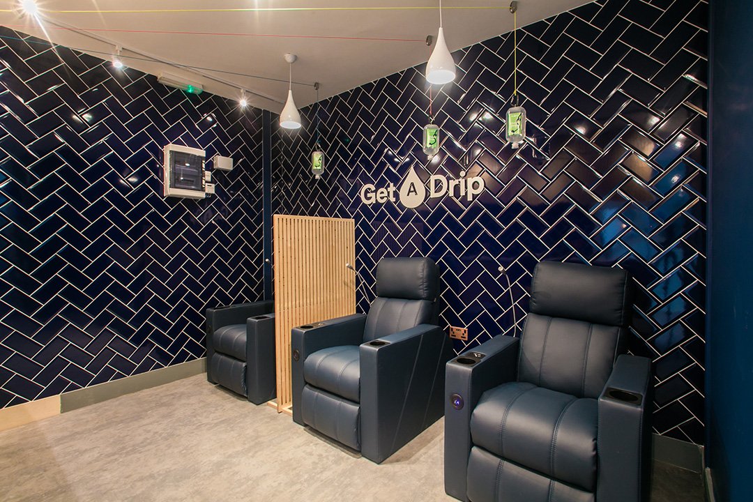 Get A Drip IV Drip room with blue recliner chairs and a blue panel wall