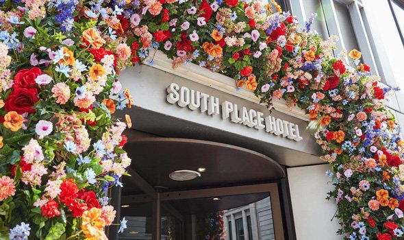 De ingang van het South Place Hotel met een kleurrijke bloemenboog